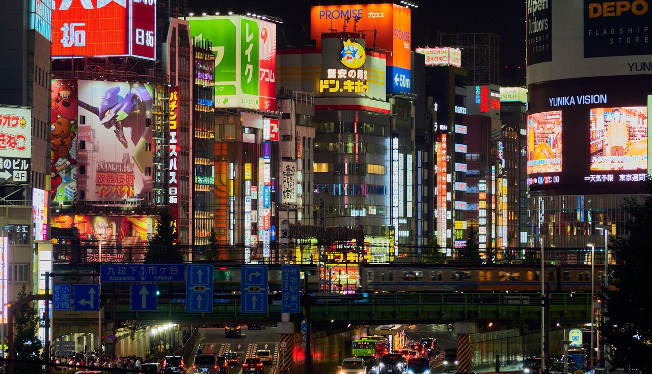 Neon shopfronts stacked up a Shinjuku facade at night.