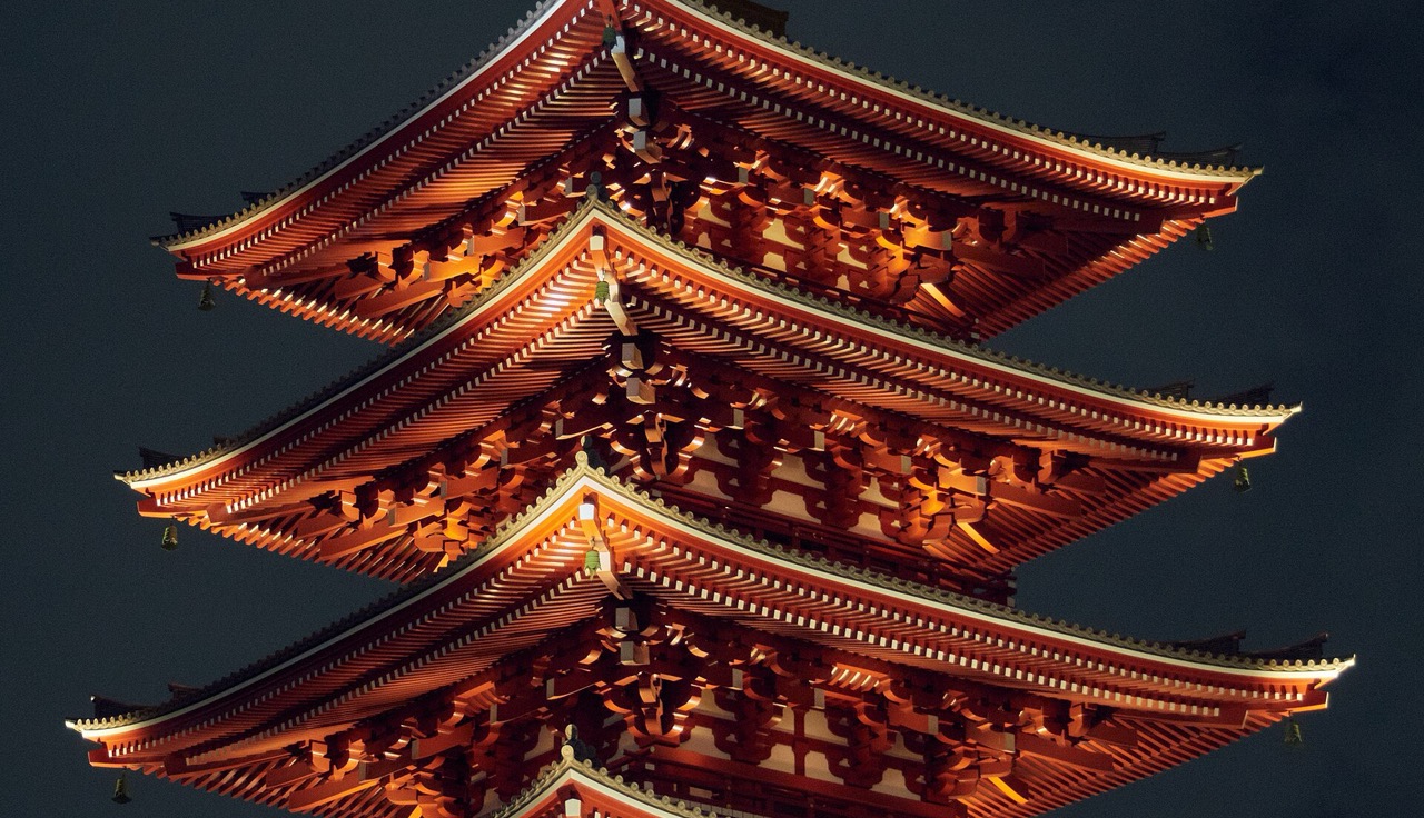 The lit eaves of the Senso-ji pagoda against a night sky.