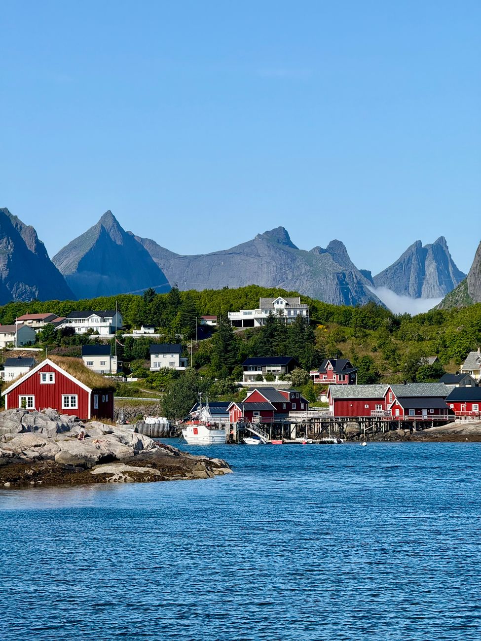 Red fishing cabins on stilts beneath steep Lofoten peaks