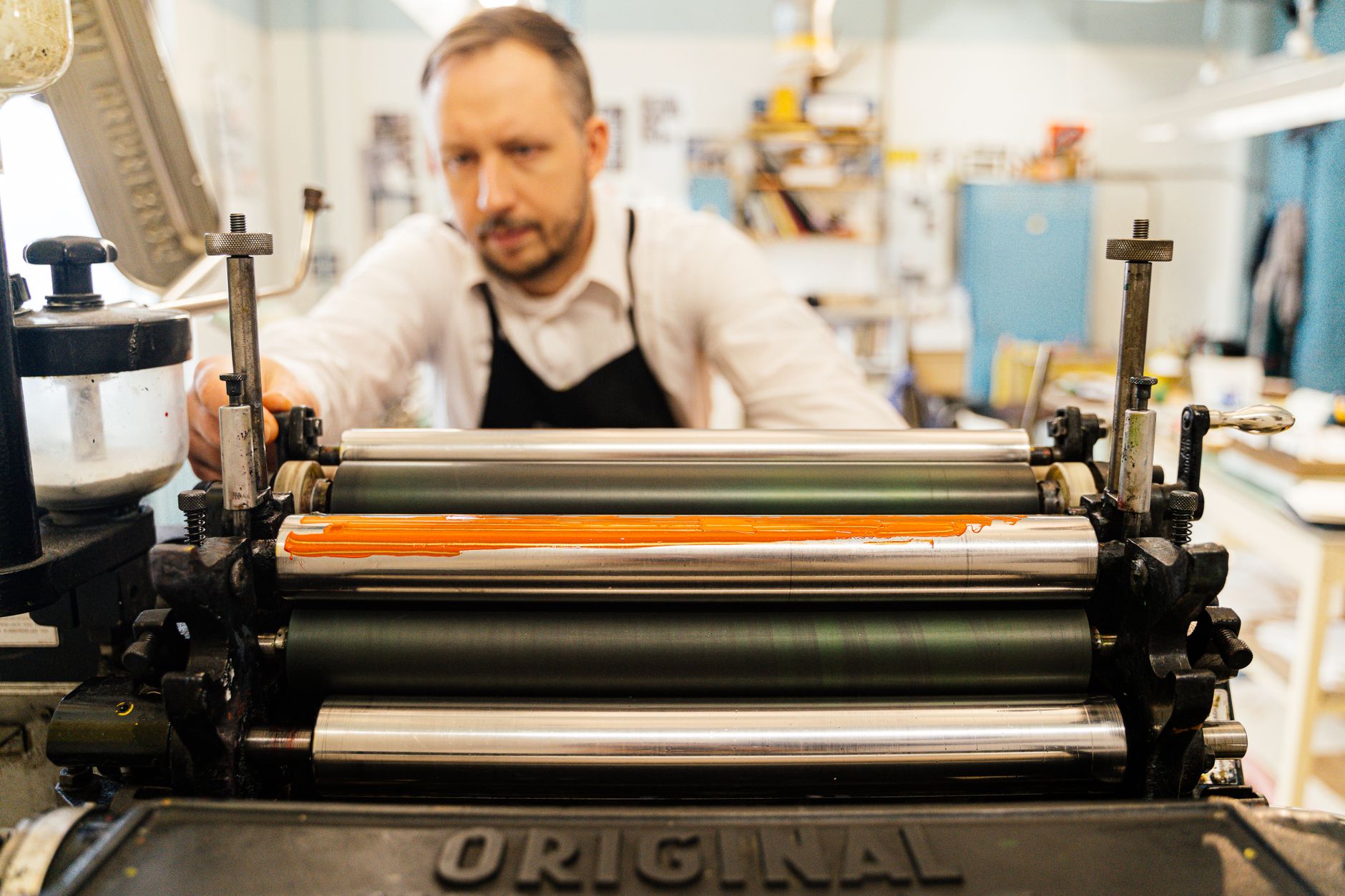 Printer feeding paper through the press rollers at Double Drum Press
