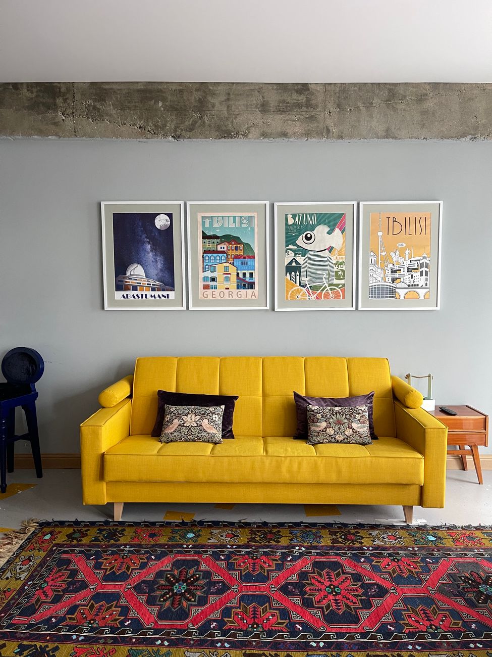 Four framed film posters hung above a yellow sofa