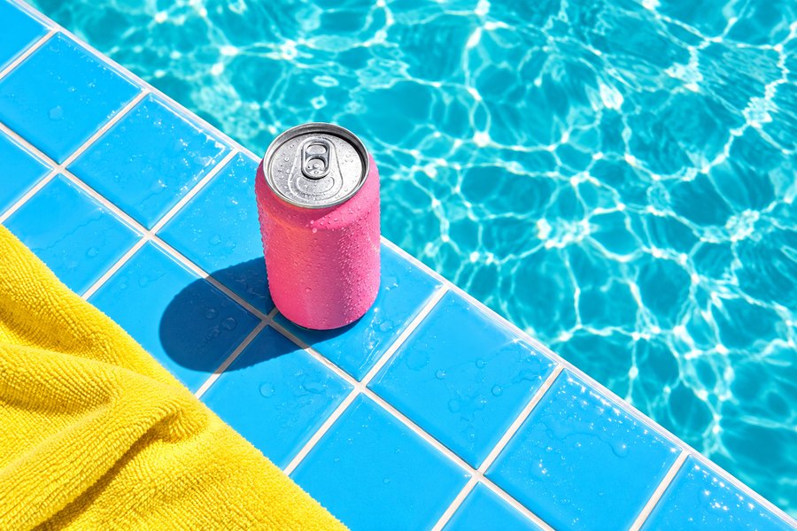 A can resting on sunny poolside tiles