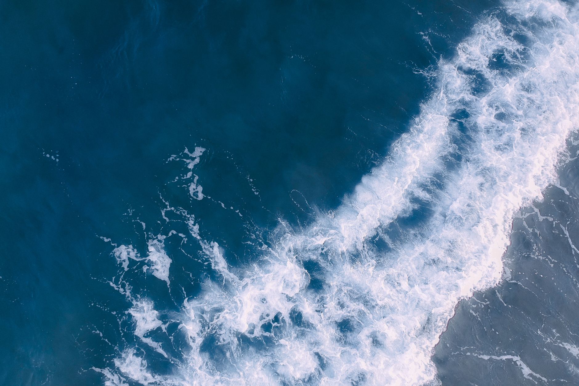 Aerial view of white-capped waves rolling over deep blue water