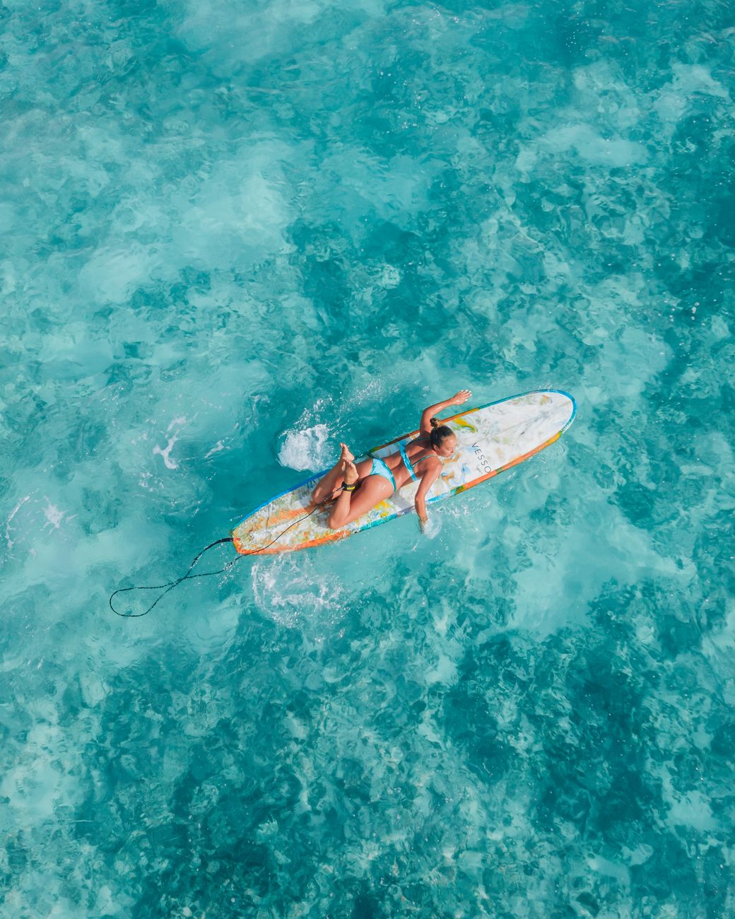 A swimmer floating in clear turquoise water in the early morning
