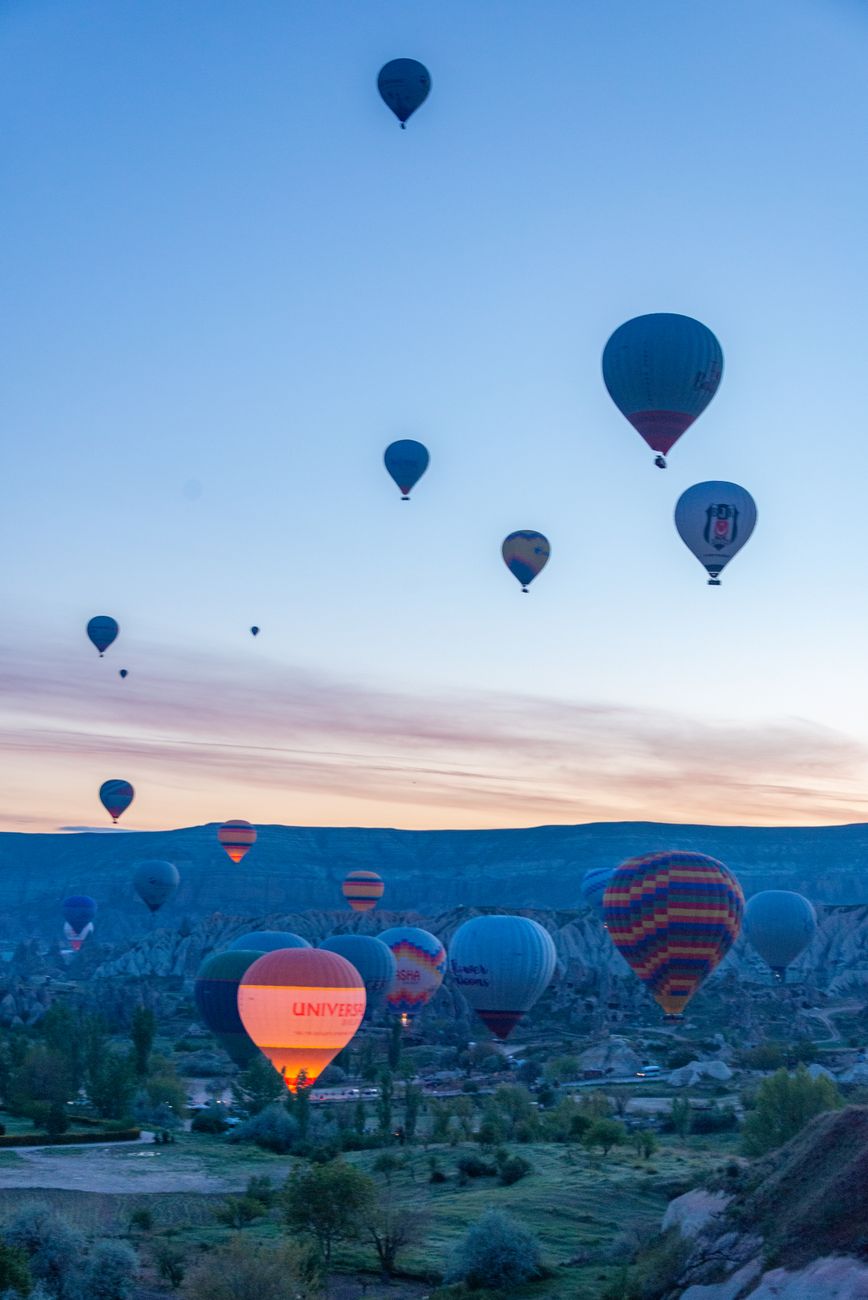 Hot air balloons drifting over a valley at sunrise
