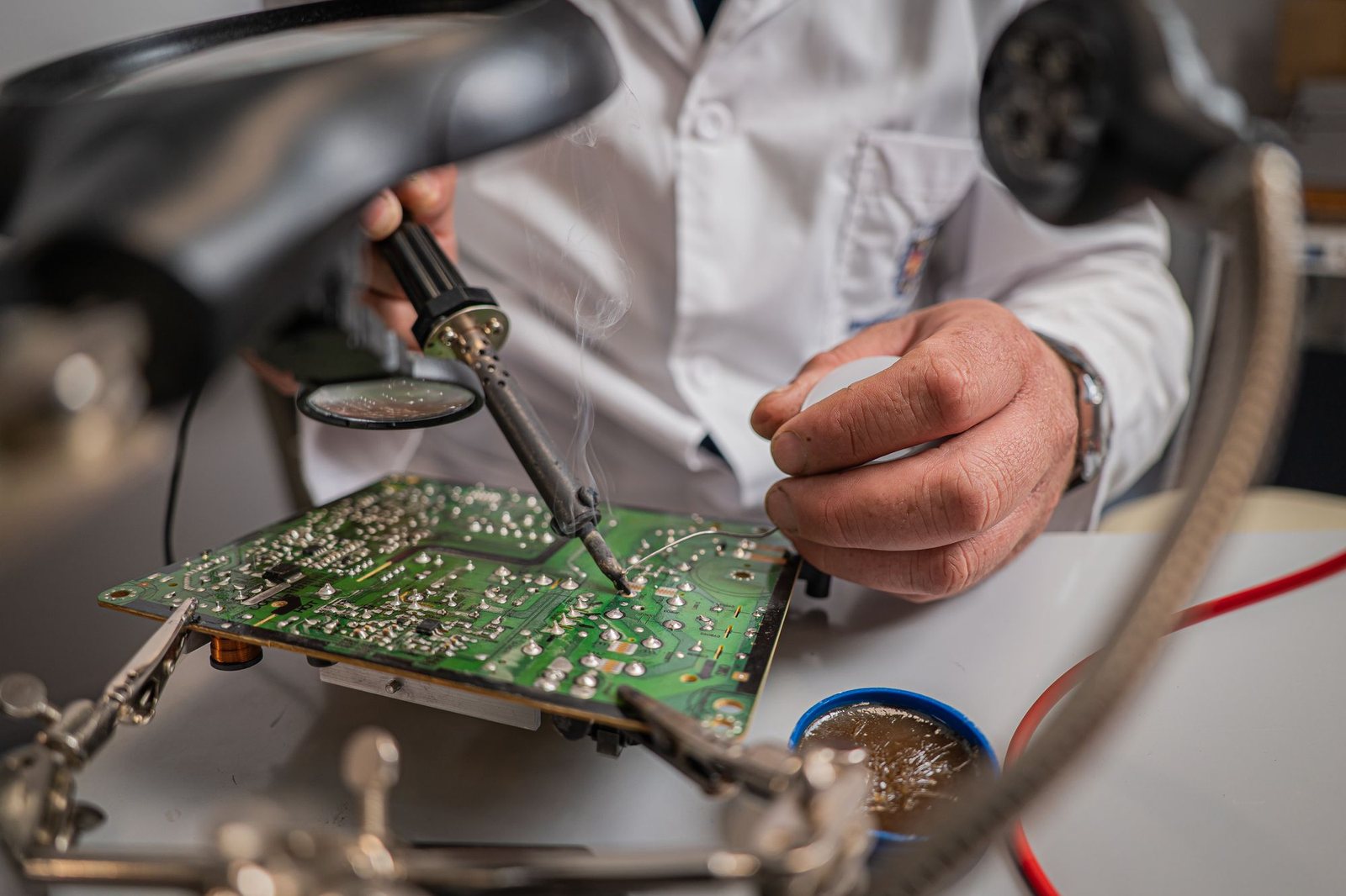 A technician solders components onto a circuit board at a workbench