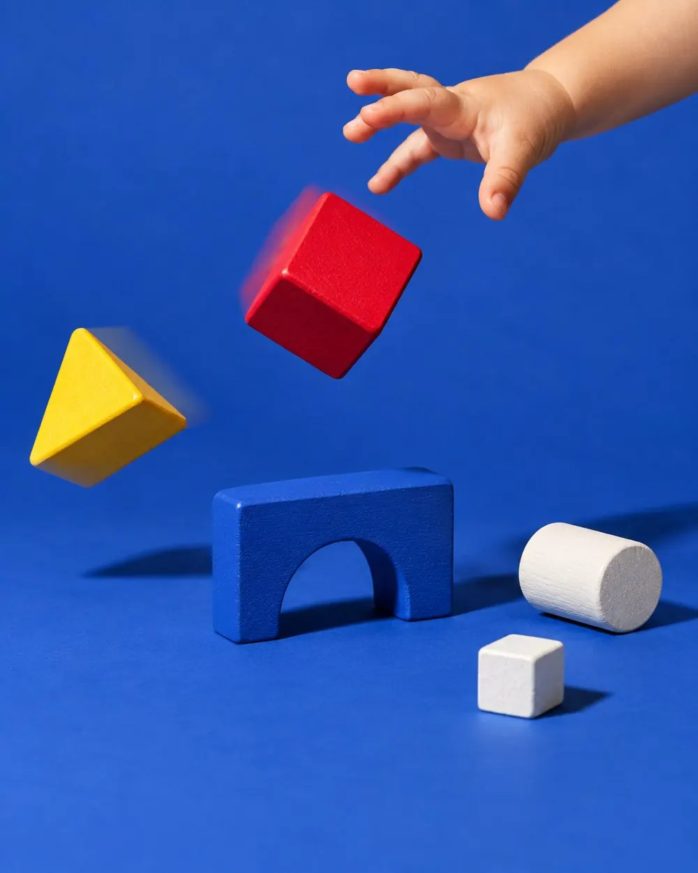 A toddler knocking the First Five tower over on blue paper