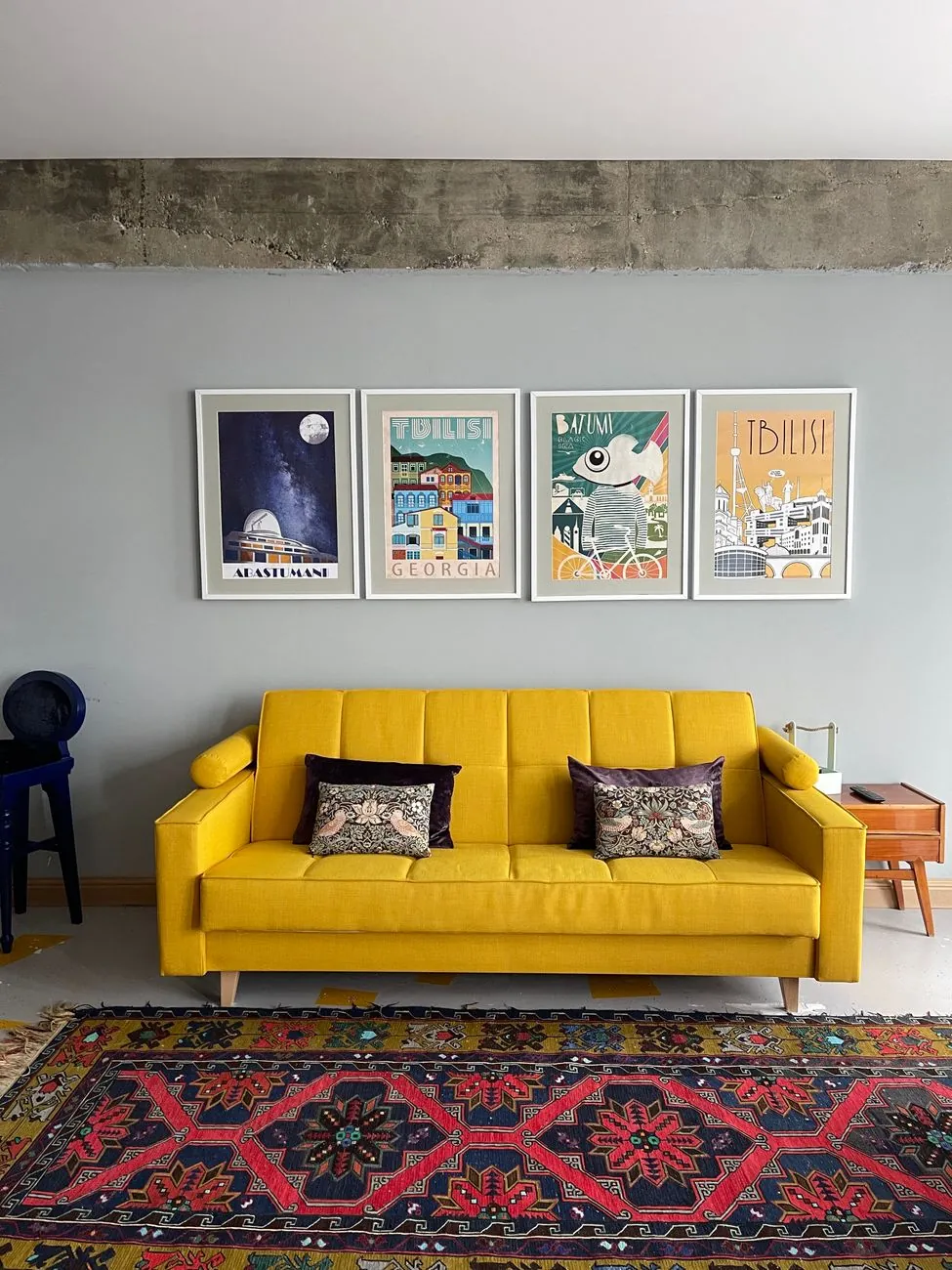 Four framed film posters hung above a yellow sofa