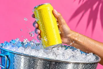 A hand pulling a cold can from an ice bucket