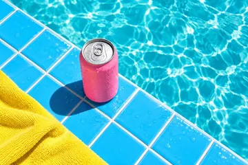 A can resting on sunny poolside tiles