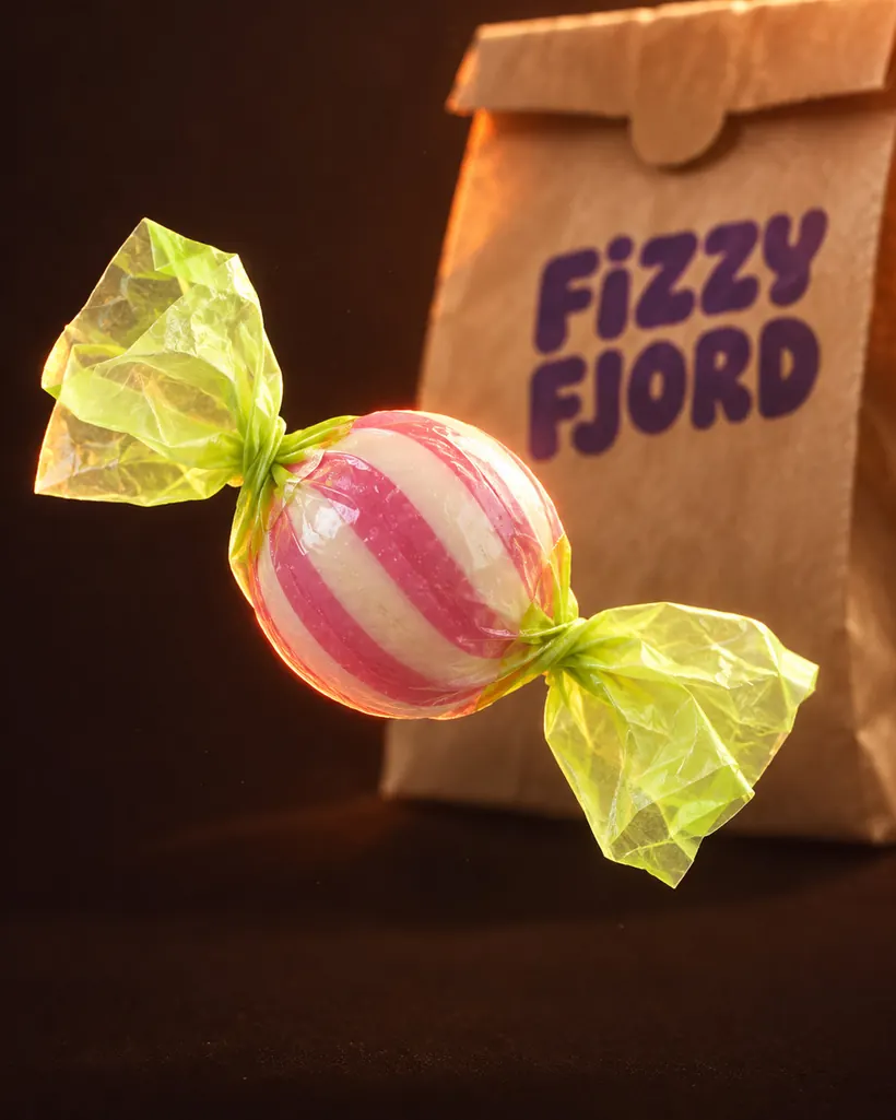 Striped hard candy in a lime cellophane twist wrapper, lit like a film still