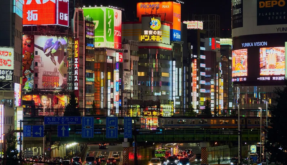 Neon shopfronts stacked up a Shinjuku facade at night.