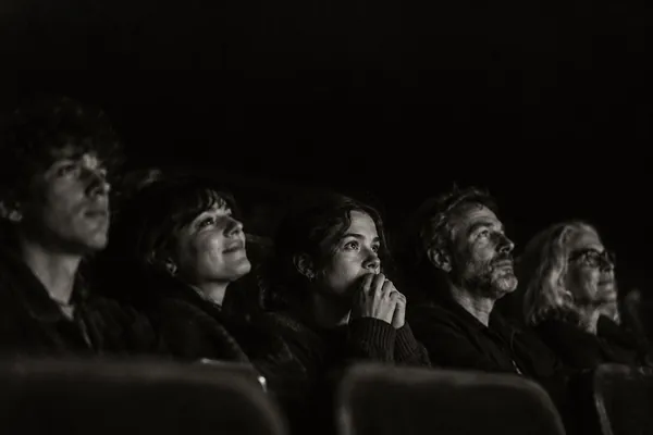 A row of audience faces lit by the screen