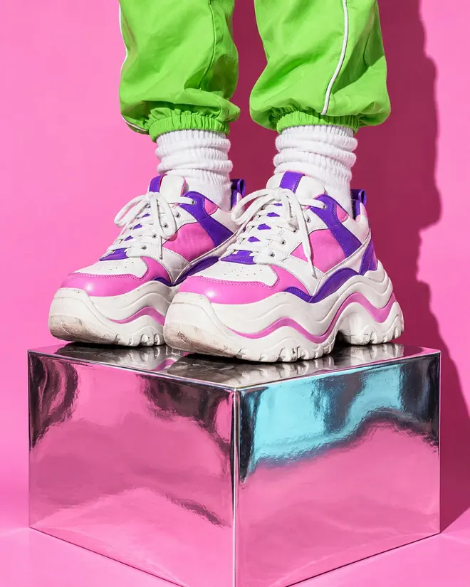 Chunky white, pink and purple platform sneakers standing on a chrome cube