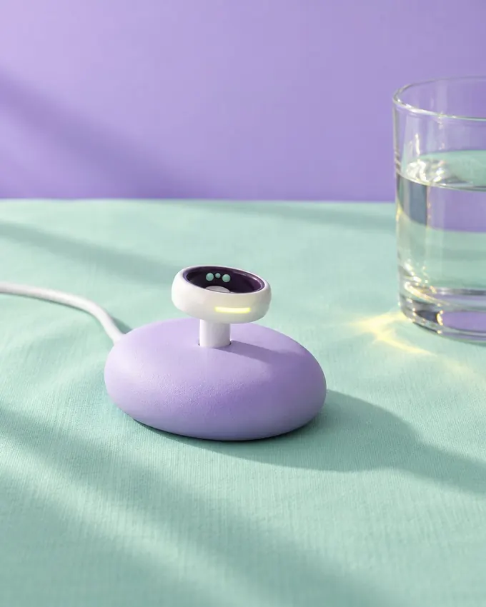 A pebble-shaped lilac charging dock on mint linen beside a glass of water