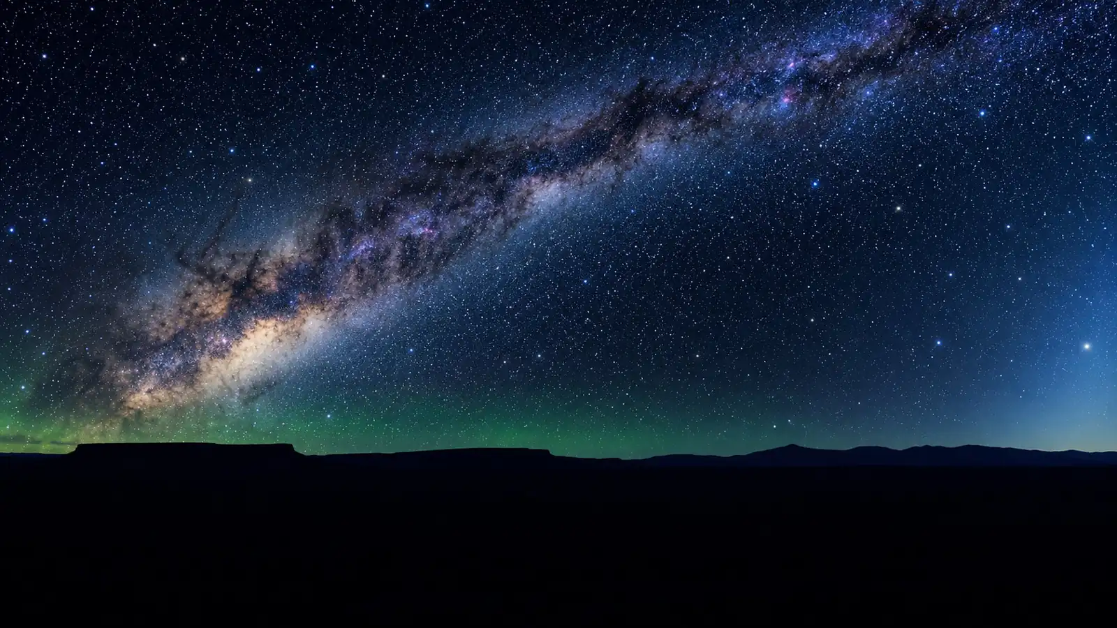 The Milky Way arching over an empty high-desert plateau at night