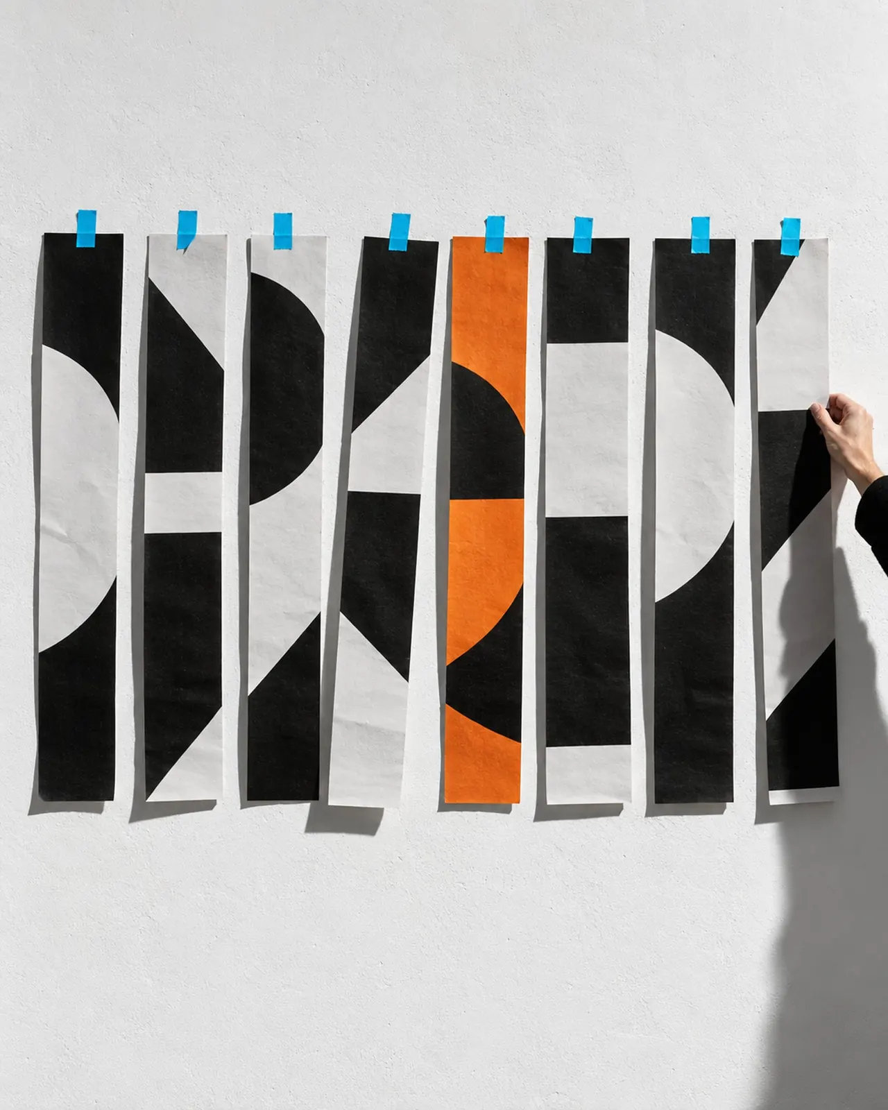 A wall poster sliced into strips and rearranged out of order, pinned with cyan tape