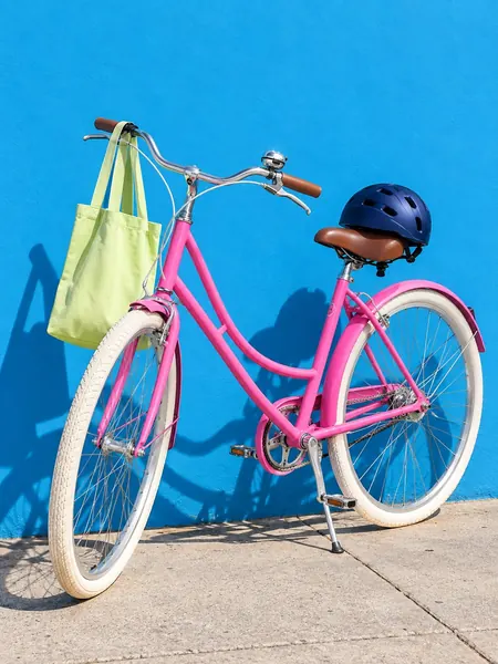 Pink city bike leaning on a sky blue wall
