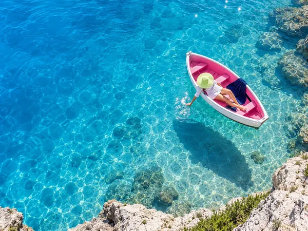 Small pink and white rowing boat floating on clear blue water