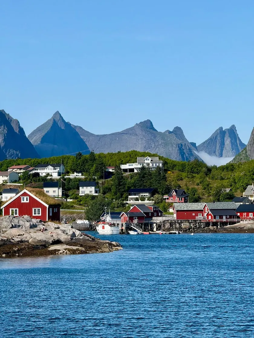 Red fishing cabins on stilts beneath steep Lofoten peaks