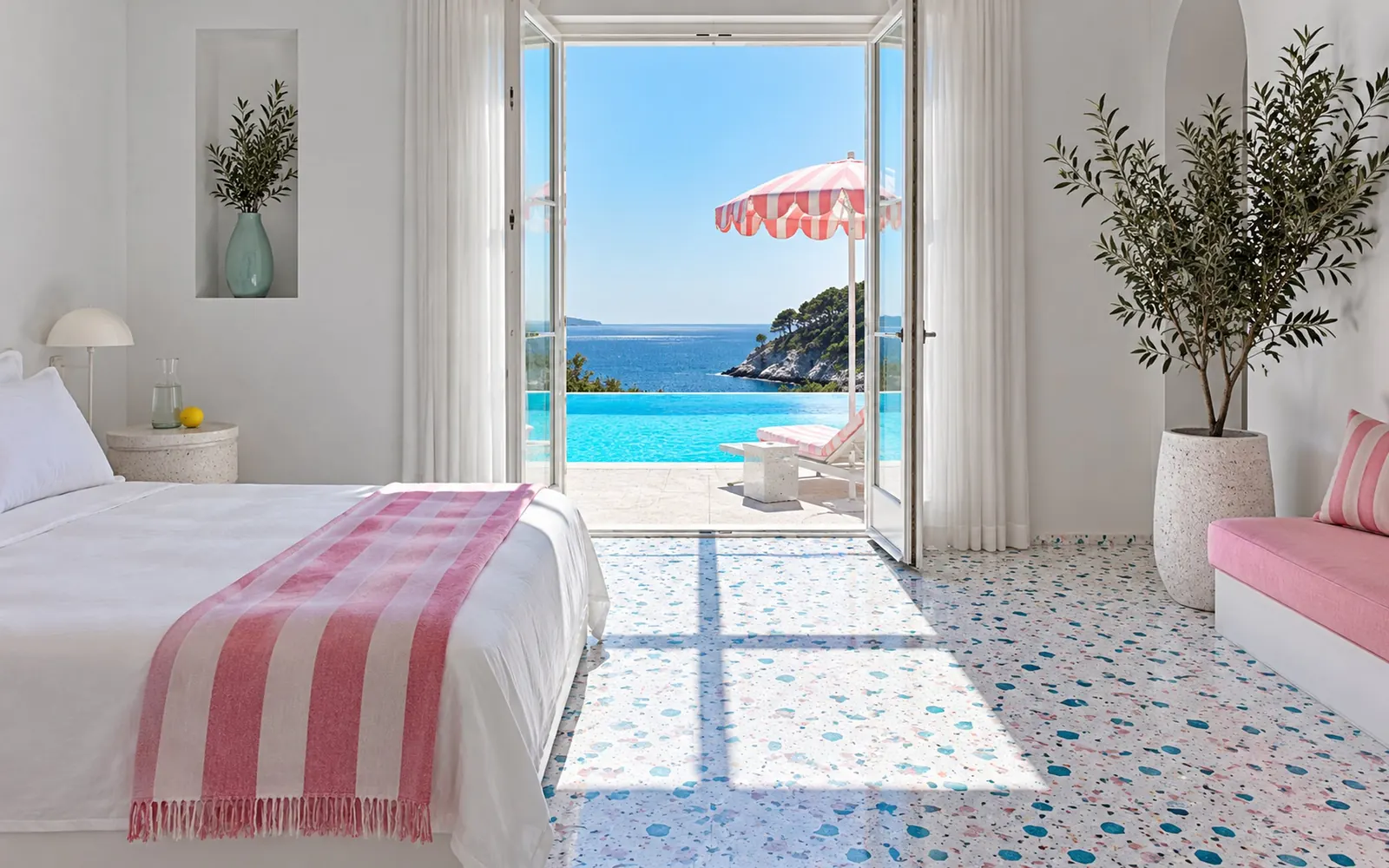A white pool-side room at noon, its glass door open onto blue water, a striped pink throw at the foot of a low white bed.