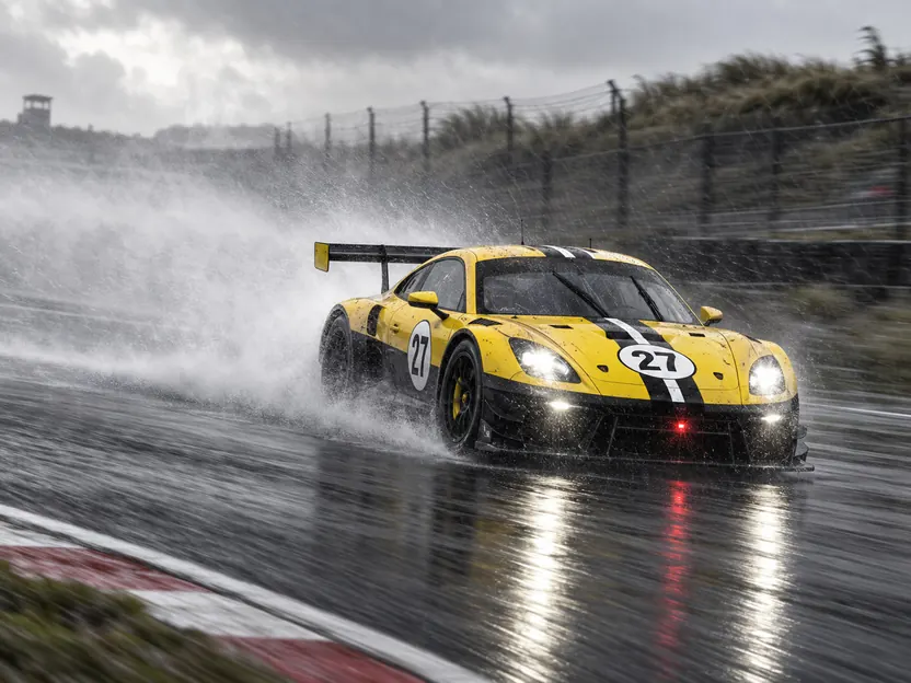 Car 27 throwing spray on a wet track, headlights on