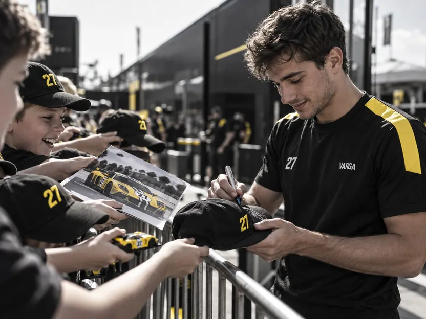 Luca signing caps for young fans at the paddock fence