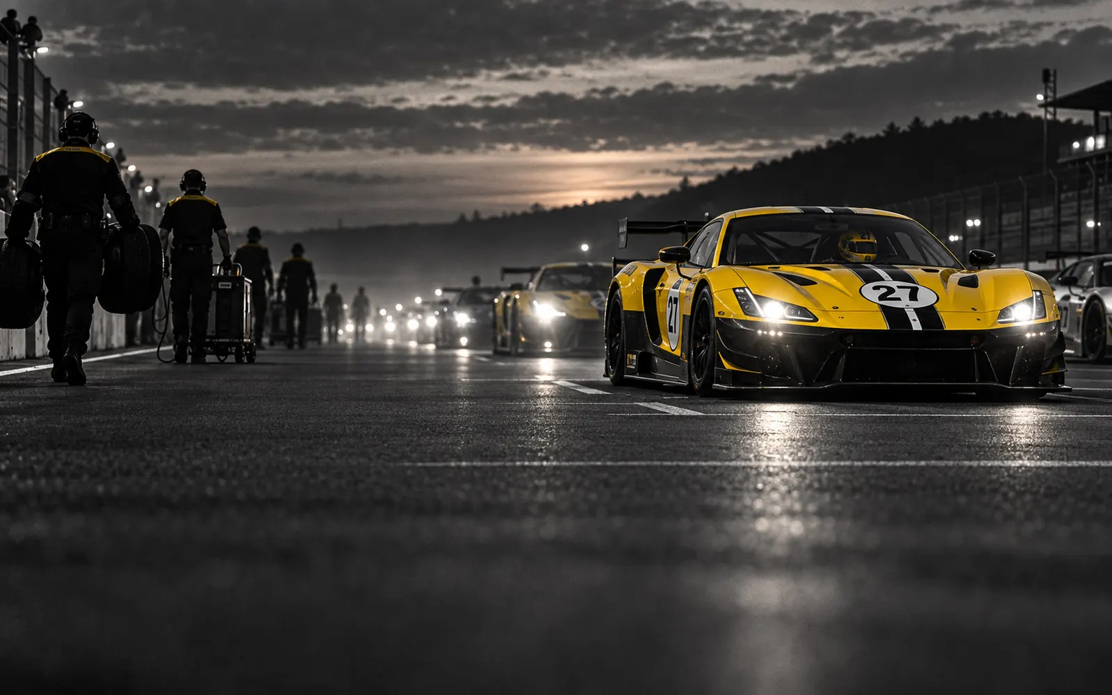 The GT3 Cup grid lined up at dusk, headlights on, mechanics leaving the track